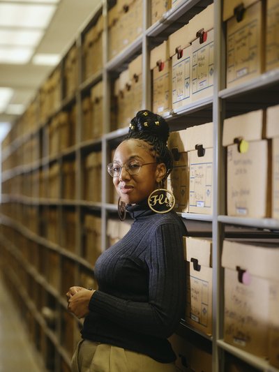 Photo of Lae'l Hughes-Watkins in front of archival boxes