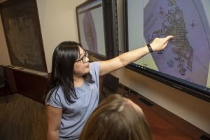 Graduate fellow points at map on screen