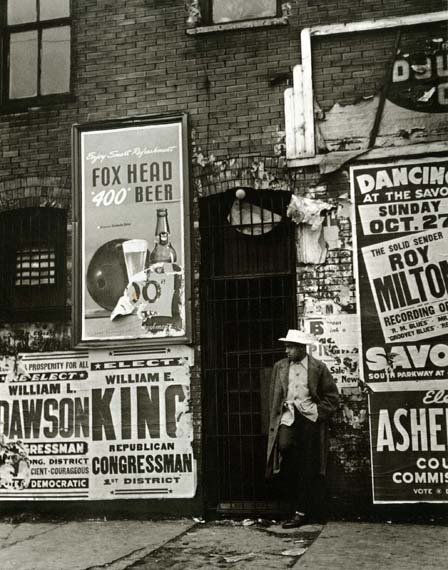 A wall papered over with advertisements for Fox Head beer and congressmen.