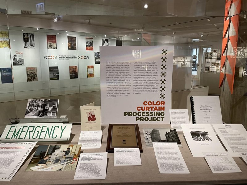 Case on the Color Curtain Processing Project in the foreground with book jackets displayed in the background of the exhibition gallery