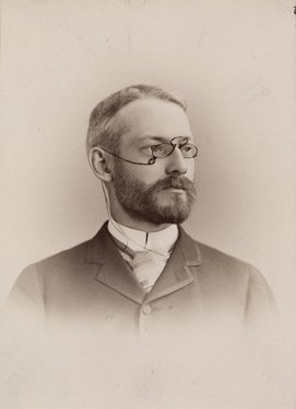 An old photograph of a suited man wearing a monocle.