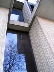 A concrete building with a tree reflected in its window.