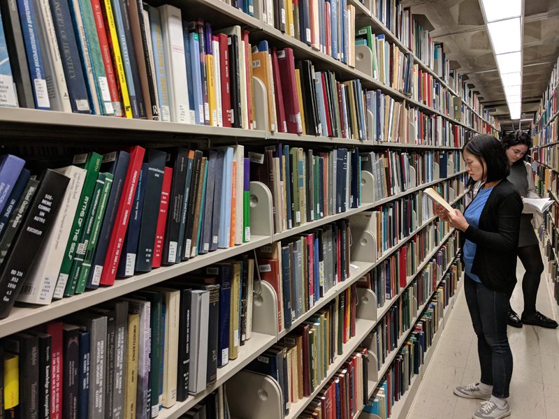Two students look at books in the Regenstein stacks