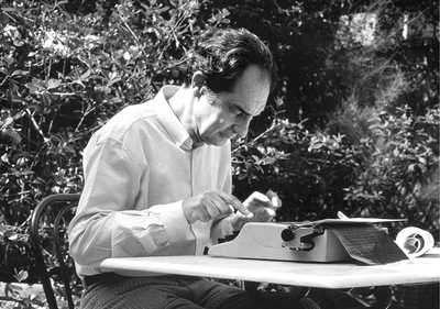 A black and white photograph of Italo Calvino writing on a typewriter.