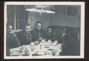 Harry Johnson with others seated around a table with plates and cups