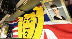 A wide cloth with a man's face in yellow in the center, and different red, white, and blue designs behind.
