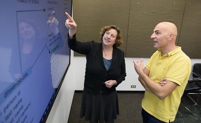 Stefano Allesina discusses a data management plan with Elisabeth Long, who points sto the plan on screen.