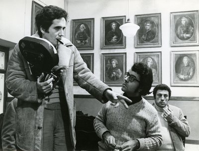 A black and white photograph of Marco Bellocchio giving film direction while holding a camera.