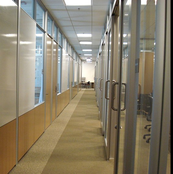 A hallway with glass walls on one side, wooden on the other.