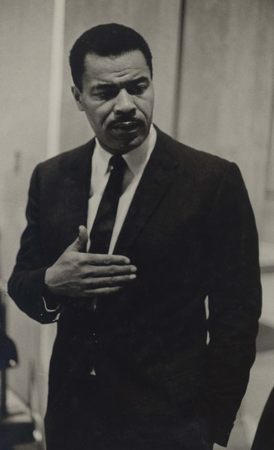 Portrait of Paul Moses. He is speaking and gesturing with his right hand