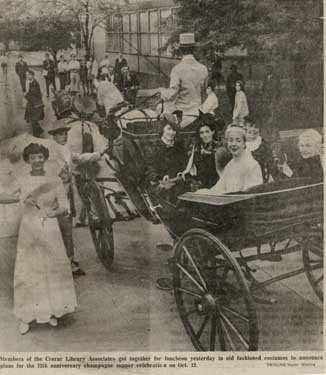 Women sitting in a horse-drawn carriage smile at the camera.