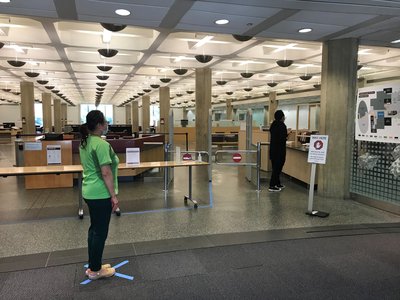 Two socially distanced individuals wait to pick up materials in Regenstein's outer lobby.