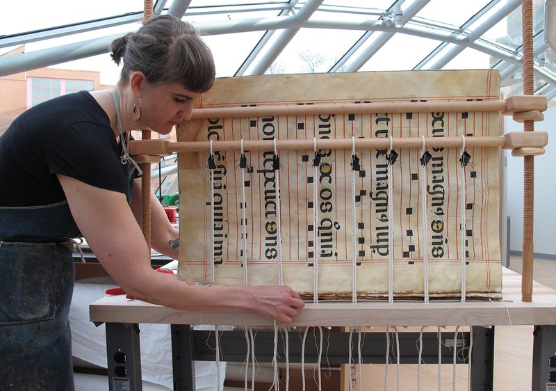 Melina Avery binds a large music book under the Mansueto Library dome