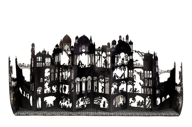 A black and white image of a laser-cut accordion book of a fantastical kingdom