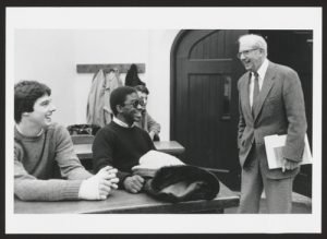 Three seated students with George Stigler, standing.