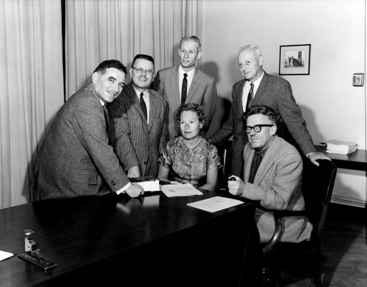 A group of men and one woman sit around a table.