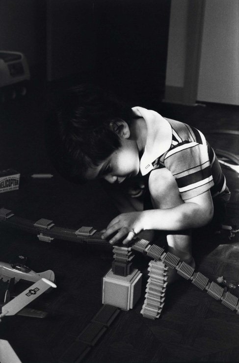 Photograph of boy playing with toys.