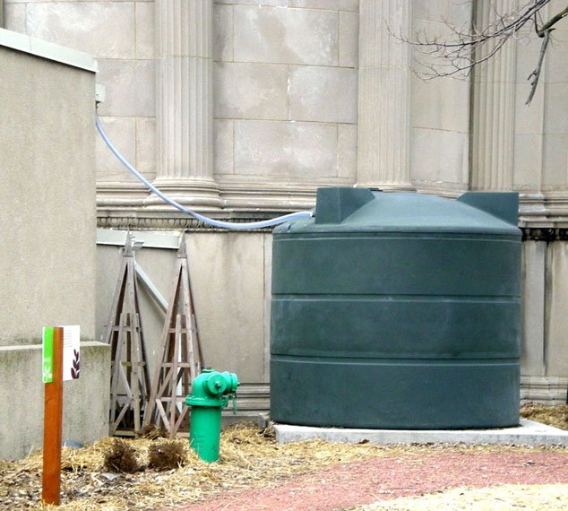 A green basin with a tube attaching it to a concrete building.