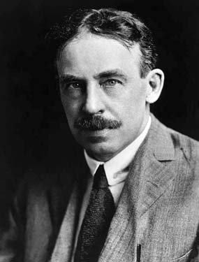 Headshot of a man, with a mustache, wearing a suit.