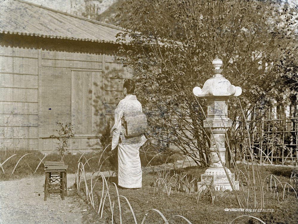A woman in a kimono stands in the Japanese Garden. Her back is to the camera.