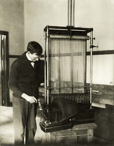 A man adjusts a complex, stringed instrument.