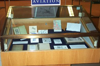 An exhibit case holding papers, books, and photographs.