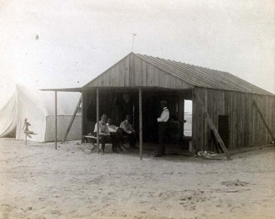 A few men sit inside a wooden shed.