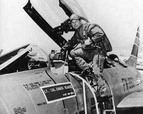 A pilot in combat gear climbing into a WWII-era plane.
