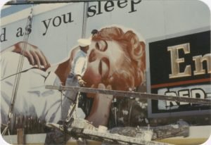 Man working on billboard featuring woman