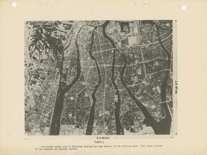 A black and white aerial photo of the city of Hiroshima before the bomb strike. Five river branches wind through the densely packed city.