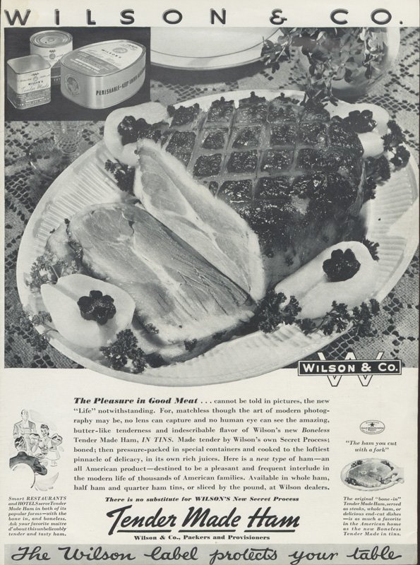 Full-page black-and-white advertisement for Wilson & Co. "Tender Made Ham." Depicts a photograph of a prepared ham on a serving platter with poached pears. The platter rests on a lace tablecloth. Two other inset illustrations include a picture of Wilson tinned meats, and a drawing of a couple dining in a restaurant. Slogan reads "The Pleasure in Good Meat...cannot be gold in pictures, the new "Life" notwithstanding. For, matchless though the art of modern photography may be, no lens can capture and no human eye can see the amazing, butter-like tenderness and indescribable flavor of Wilson's new Boneless Tender Made Ham, IN TINS."