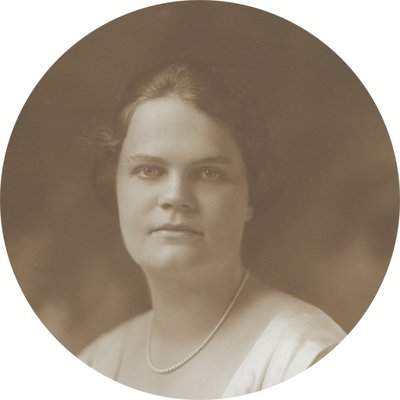Black-and-white formal photographic portrait of Helen Wilson Williams, circa 1910s-1920s. She is a young, white woman with dark hair that is pinned up. She is wearing a light-colored dress and looking directly into the camera.