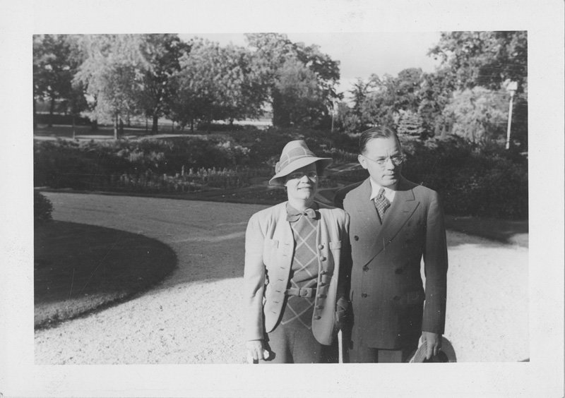 Black-and-white snapshot of Helen Wilson Williams. The photograph is from the same day and place as the preceding photograph. Helen is shown standing next to her husband who is a white man wearing a suit and glasses, and holding a hat in his hand. The two may be shown on the grounds of Edellyn Farms.