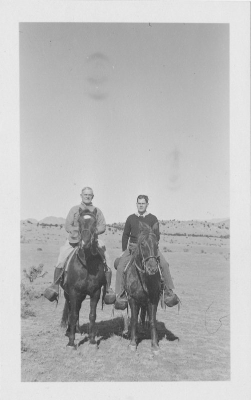 Black-and-white photograph of Thomas E. Wilson and Edward Foss Wilson seated on horses. Both are white men and are facing the camera. They are in the desert.